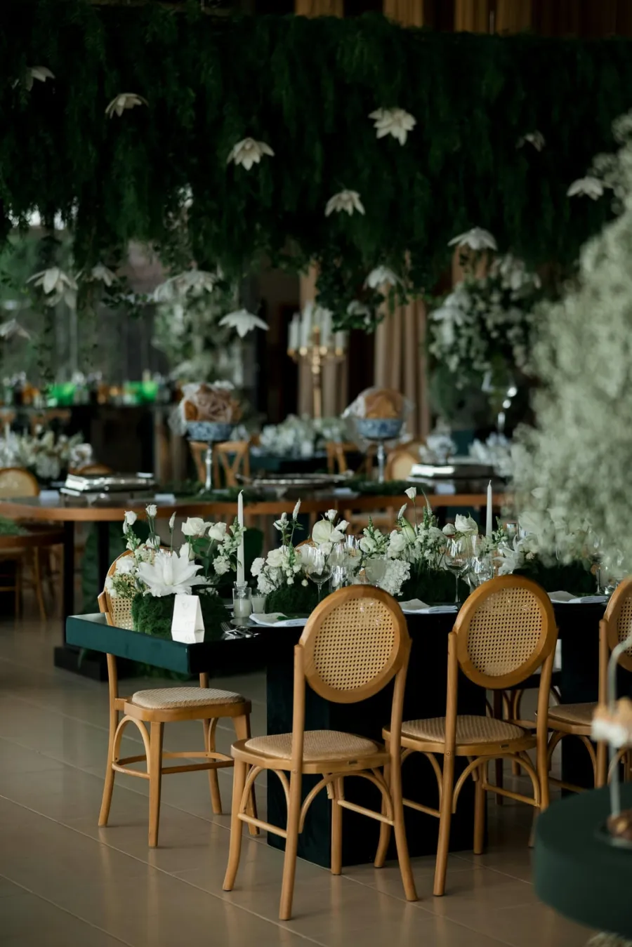 Mesa de jantar ao ar livre com arranjos verdes e brancos